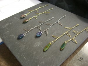 Three pairs of wire earrings, shaped like vines, with glass beads dangling at the end.