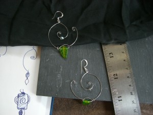 Earrings made with wire shaped into two spirals, with glass beads dangling from them.